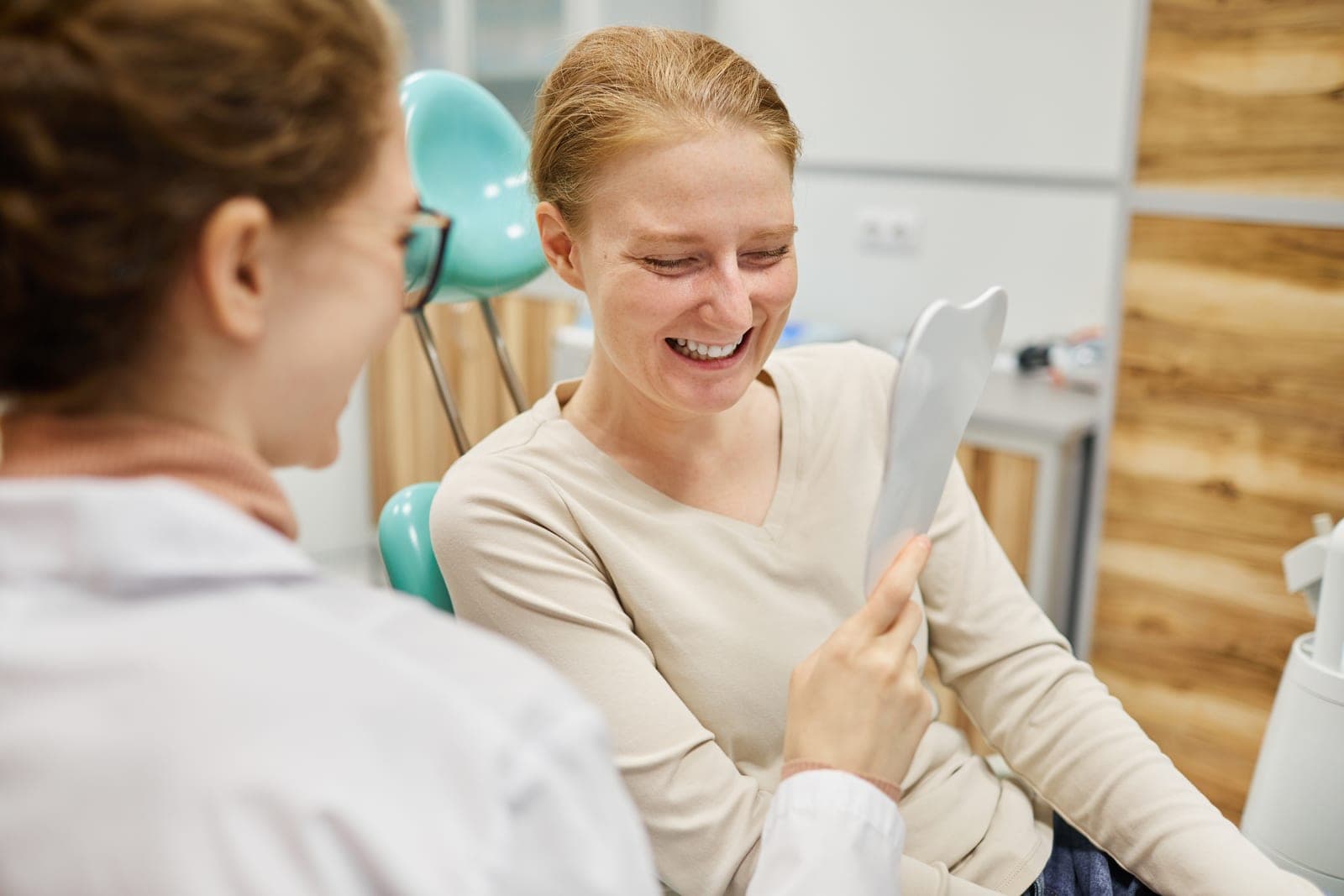 A patient smiling as she sees her healthy smile in a mirror at Marchwood Dental Practice